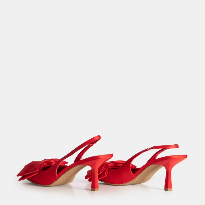 Red satin slingback heels with decorative bow detail showing heel profile and slim heel fashion style.